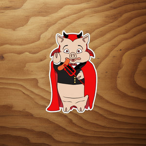Rudy’s Bar & Grill Devil Pig sticker in a Dracula costume on a plain rustic wood background.