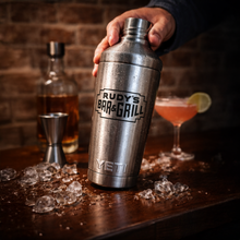 Load image into Gallery viewer, Stainless steel Rudy’s Bar &amp; Grill YETI cocktail shaker standing on a wooden bar against a brick wall.