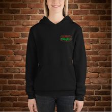 Load image into Gallery viewer, Woman wearing Rudy’s Bar &amp; Grill Baron Von Swine Christmas Light Edition unisex hoodie, featuring festive Rudy’s Bar &amp; Grill logo on the front, black pullover, brick wall background