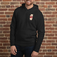 Load image into Gallery viewer, Person wearing Black hoodie featuring a small Baron Von Swine pig mascot graphic on the chest, displayed flat against a reddish-brown textured brick wall background. The hoodie is centered and well-lit for a realistic