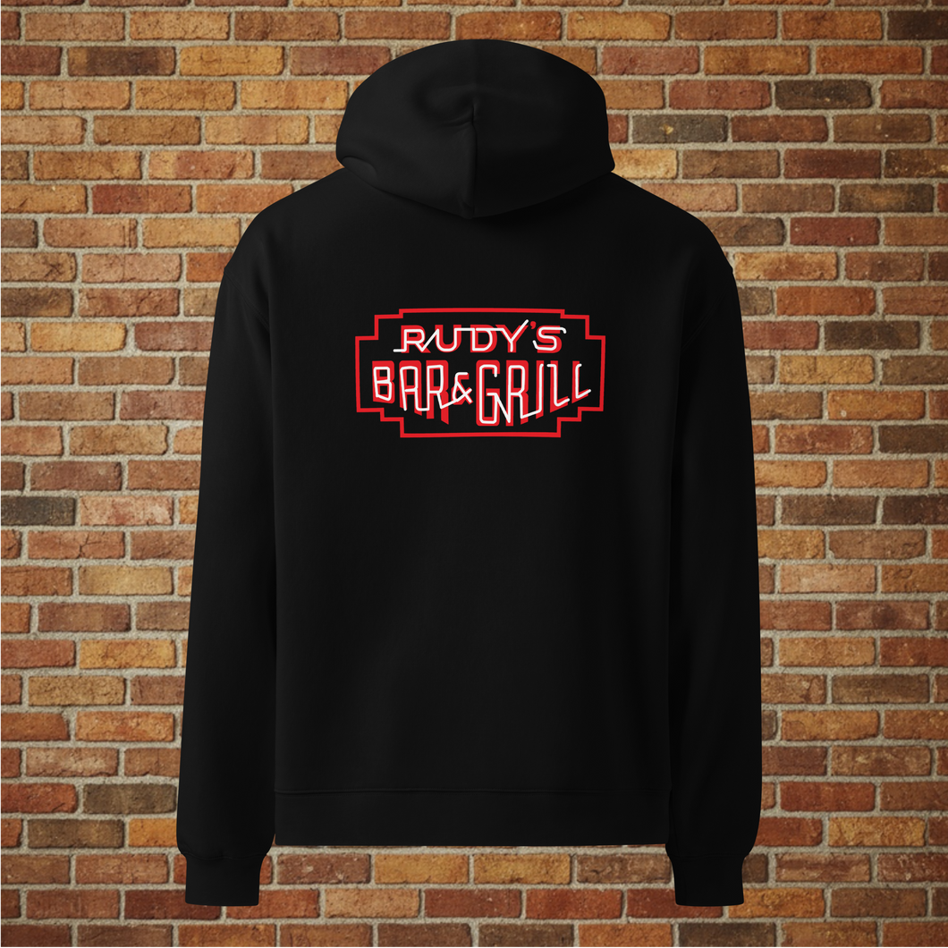 Back view of Rudy’s Bar & Grill Hot Dog Neon Hoodie in black with neon bar sign, displayed against a brick wall background.