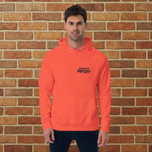 Load image into Gallery viewer, Front view of burnt orange unisex eco raglan hoodie with Rudy&#39;s Bar &amp; Grill logo on chest, worn by model against brick wall