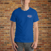 Load image into Gallery viewer, Model wearing Classic Rudy’s Bar &amp; Grill true royal blue t-shirt, front view with small logo, brick wall background