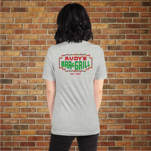 Load image into Gallery viewer, Back of Rudy’s Bar &amp; Grill Christmas Neon Sign T-Shirt – festive NYC dive bar logo with holiday lights, brick wall background