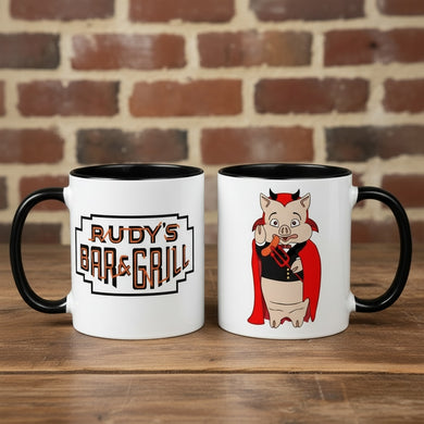 Rudy’s Bar & Grill Halloween coffee mugs showing both sides—one with the classic Rudy’s logo, one with the devil pig cartoon—on a rustic wood bar with a brick wall background