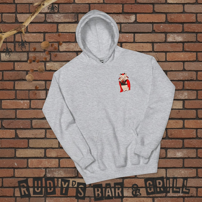 Flat lay of a sport grey hoodie with a small Baron Von Swine devil pig mascot on the chest, arranged on a reddish-brown brick wall background with Halloween-themed props and “Rudy’s Bar & Grill” spelled out at the bottom.