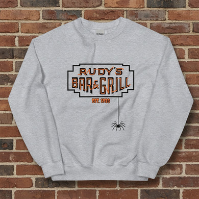 Sport grey crew neck sweatshirt with Rudy’s Bar & Grill Halloween logo and hanging spider, displayed flat against a reddish-brown brick wall background.