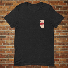 Load image into Gallery viewer, Front view of a black heather t-shirt with a small Baron Von Swine pig logo on the chest, modeled in front of a brick wall.