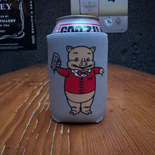 Load image into Gallery viewer, Retro style can koozie featuring Baron Von Swine mascot in a red jacket, set on a wooden bar with a dark textured wall behind