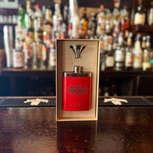 Load image into Gallery viewer, Rudy’s Bar &amp; Grill red Yeti flask with matching funnel shown in open gift box on a bar, with liquor bottles blurred in the background