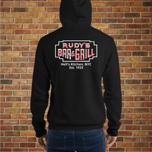 Load image into Gallery viewer, Back view of Rudy’s Bar &amp; Grill Baron Von Swine Neon Sign Hoodie worn by a model – black pullover featuring the neon sign logo and &quot;Hell’s Kitchen, NYC Est. 1933&quot; text, shown against a brick wall background