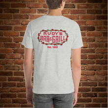Load image into Gallery viewer, Back view of Rudy’s Bar &amp; Grill athletic heather t-shirt with neon sign and Est. 1933, brick wall background