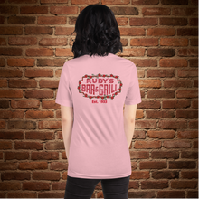 Load image into Gallery viewer, Back view of Rudy’s Bar &amp; Grill pink t-shirt with classic neon sign and Est. 1933, brick wall background