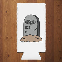 Load image into Gallery viewer, Rudy’s Bar &amp; Grill Halloween can cooler featuring a tombstone graphic with “Rudy’s Bar &amp; Grill 1933–” on a white slim koozie, wood background