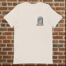 Load image into Gallery viewer, Front view of Rudy’s Bar &amp; Grill Halloween Edition heather dust t-shirt with a tombstone graphic reading &quot;Rudy’s Bar &amp; Grill 1933-&quot; on the left chest, set against a brick wall background