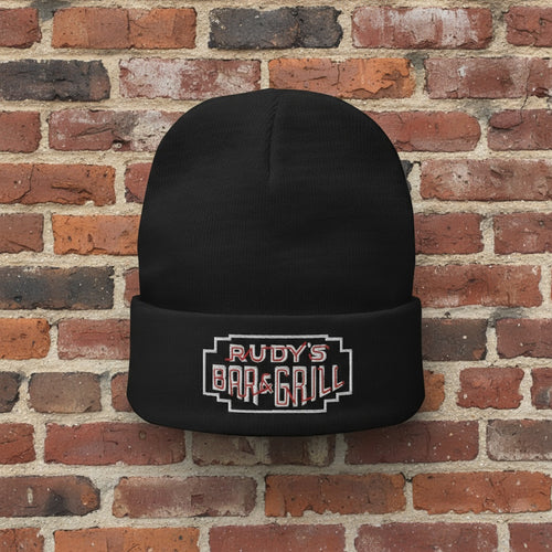 Rudy’s Bar & Grill Neon Sign Cuff Beanie displayed against a brick wall