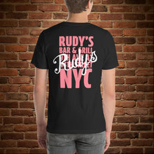 Load image into Gallery viewer, Man wearing Rudy’s Bar &amp; Grill Valentine’s Day NYC Edition T-shirt, back view – bold pink NYC logo and script on black shirt, brick wall background