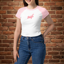 Load image into Gallery viewer, Woman wearing Rudy’s Bar &amp; Grill women’s micro rib raglan baby tee in white with pink sleeves and Rudy’s script logo, standing in front of a brick wall