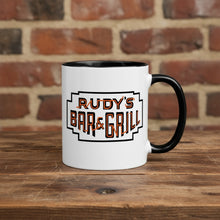 Load image into Gallery viewer, Rudy’s Bar &amp; Grill Halloween coffee mug featuring the classic Rudy’s logo, placed on a rustic wood bar with a brick wall background