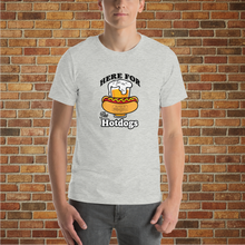 Load image into Gallery viewer, Man wearing an athletic heather &quot;Here for the Hot Dogs&quot; T-shirt from Rudy’s Bar &amp; Grill, standing in front of a brick wall background