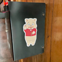Load image into Gallery viewer, Classic Rudy’s pig sticker bar logo decal on black metal box in Hell’s Kitchen ba