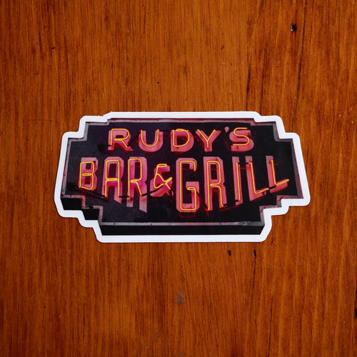 Rudy’s Bar & Grill neon sign sticker placed on a warm, rustic wood background