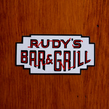 Load image into Gallery viewer, Rudy’s Bar &amp; Grill neon sign logo sticker on wood background in Hell’s Kitchen bar